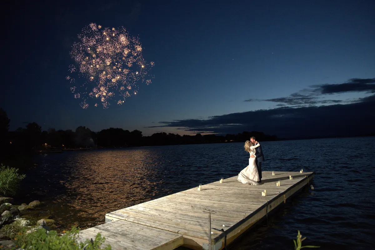 Toronto wedding couple share a kiss on a lakeside dock under fireworks